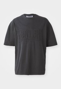 Black cotton t-shirt featuring a textured "VERTERE BERLIN" graphic on the front. Short sleeves and a crew neckline. Casual fit.