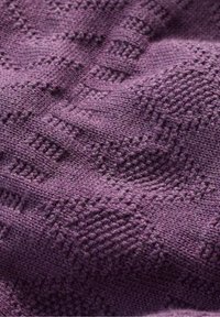 Stickad tyg i djup lila, med en texturerad design som har geometriska mönster och varierade sticktekniker för djup och visuell intresse.