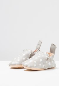 Zapatos de cuero gris suave con patrón de estrellas blancas, punta redondeada y tiradores en la parte posterior para facilitar su uso. Suela ligera para mayor comodidad.