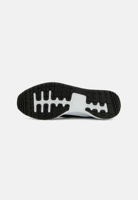 Black rubber outsole with white midsole, featuring a textured tread pattern and grooves for traction. Smooth transition to the upper section.