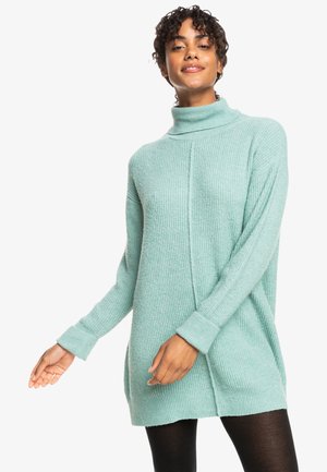 Mintgrüner, gerippter Langarmpullover mit hohem Kragen und seitlichen Schlitzen; verfügt über überschnittene Schultern und eine lässige Passform.