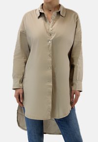 Beige Hemd mit durchgehender Knopfleiste, lockerer Passform, langen Ärmeln und abgerundetem Saum. Hergestellt aus glattem Stoff mit leichtem Glanz.