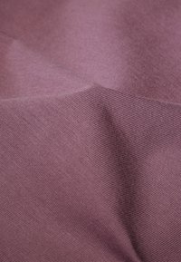 Tessuto in un colore lavanda tenue, con una superficie liscia e una leggera texture, caratterizzato da motivi a costine diagonali.