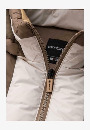 Lichte pufferjack met een tweekleurig ontwerp, met een crèmekleurig en bruin kleurenschema, een zichtbare rits en een merkaanhanger.