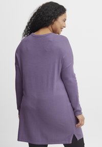 Maglione viola a maniche lunghe con una vestibilità rilassata, caratterizzato da uno spacco laterale all'orlo e un tessuto morbido e testurizzato. Design minimalista.
