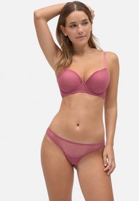 Sostenes rosa y tanga a juego con diseño de lunares, textura suave, tirantes ajustables y acentos de encaje a lo largo de los bordes.