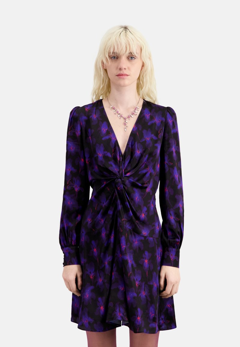 Vestido floral morado con mangas largas, fruncido en el frente, escote en v y tela texturizada. Combinado con un collar rosa y pantys.