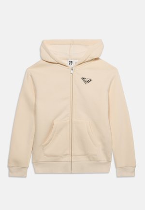 Beiger Kapuzenpullover mit Reißverschluss, Fronttaschen, Kapuze und kleinem schwarz-weißem herzförmigem Logo auf der linken Brust.