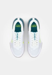 White mesh athletic shoes with a textured surface, featuring a green and blue accent and "AIR MAX" branding on the tongue.