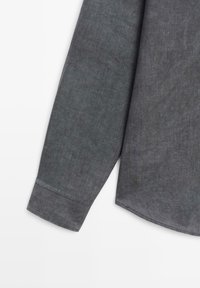 Langdonige antracietgrijze shirtmouw met een manchet, die fijne stofstructuur toont op een witte achtergrond.
