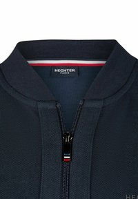 Marineblaues Zip-Jackett aus strukturiertem Stoff, mit geripptem Kragen und einem kontrastierenden Streifenakzent unter dem Kragen. Mit Hechter Paris-Label.