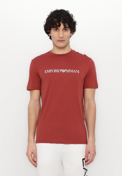 Tricou roșu din bumbac, cu guler rotund, mâneci scurte și logo-ul "EMPORIO ARMANI" imprimat alb pe piept.