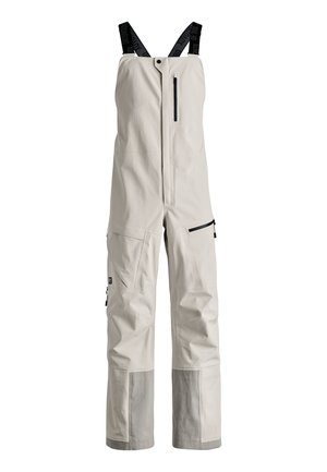 Light beige overalls made of durable fabric, featuring adjustable black suspenders, a front zipper, and multiple zip pockets for storage.