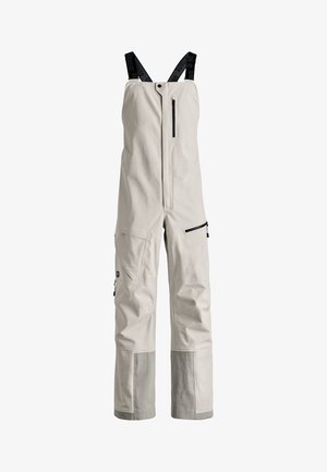 Light beige overalls made of durable fabric, featuring adjustable black suspenders, a front zipper, and multiple zip pockets for storage.