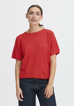 Roter, gestrickter Pullover mit kurzen Ärmeln und Rundhalsausschnitt. Weiche Textur, lockere Passform und gerippter Saum. Getragen mit dunklen Jeans.