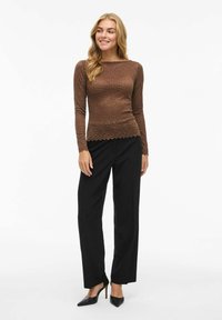 Bruine geribde langemouwen top met een scalloped zoom, gecombineerd met zwarte wijde broek en zwarte puntige hakken.