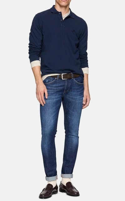 Polo a maniche lunghe navy, abbinato a jeans slim-fit blu, cintura marrone e scarpe eleganti marroni scure, con polsini risvoltati.