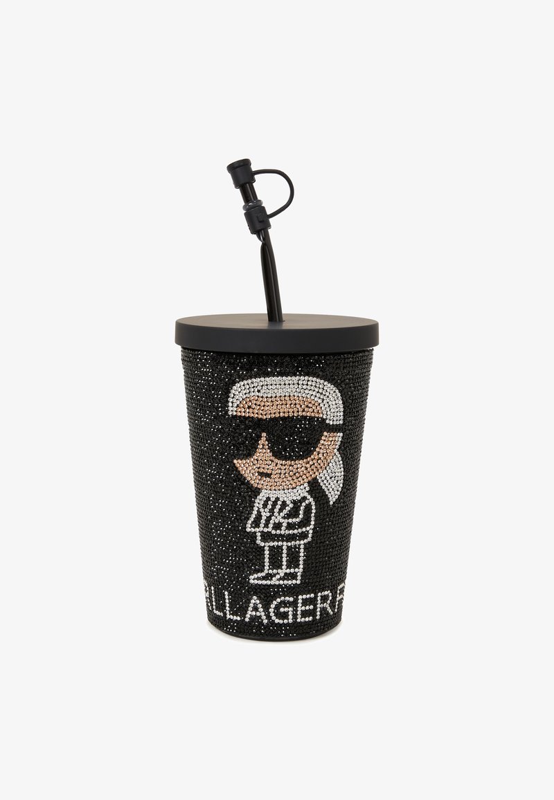 Musta kuppi, joka on peitetty strasseilla ja jossa on piirros hahmosta aurinkolaseissa, musta kansi ja musta pilli. Teksti lukee "KARL LAGERFELD."