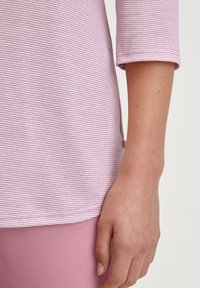 Lichtroze gestreepte top met driekwartmouwen, voorzien van een zachte textuur en een afgeronde zoom, gecombineerd met effen roze leggings.