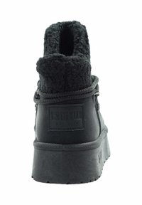 Czarny sneaker za kostkę z miękkim kołnierzem, teksturowanym materiałem, zaokrąglonym noskiem, grubą podeszwą i logo marki z tyłu.