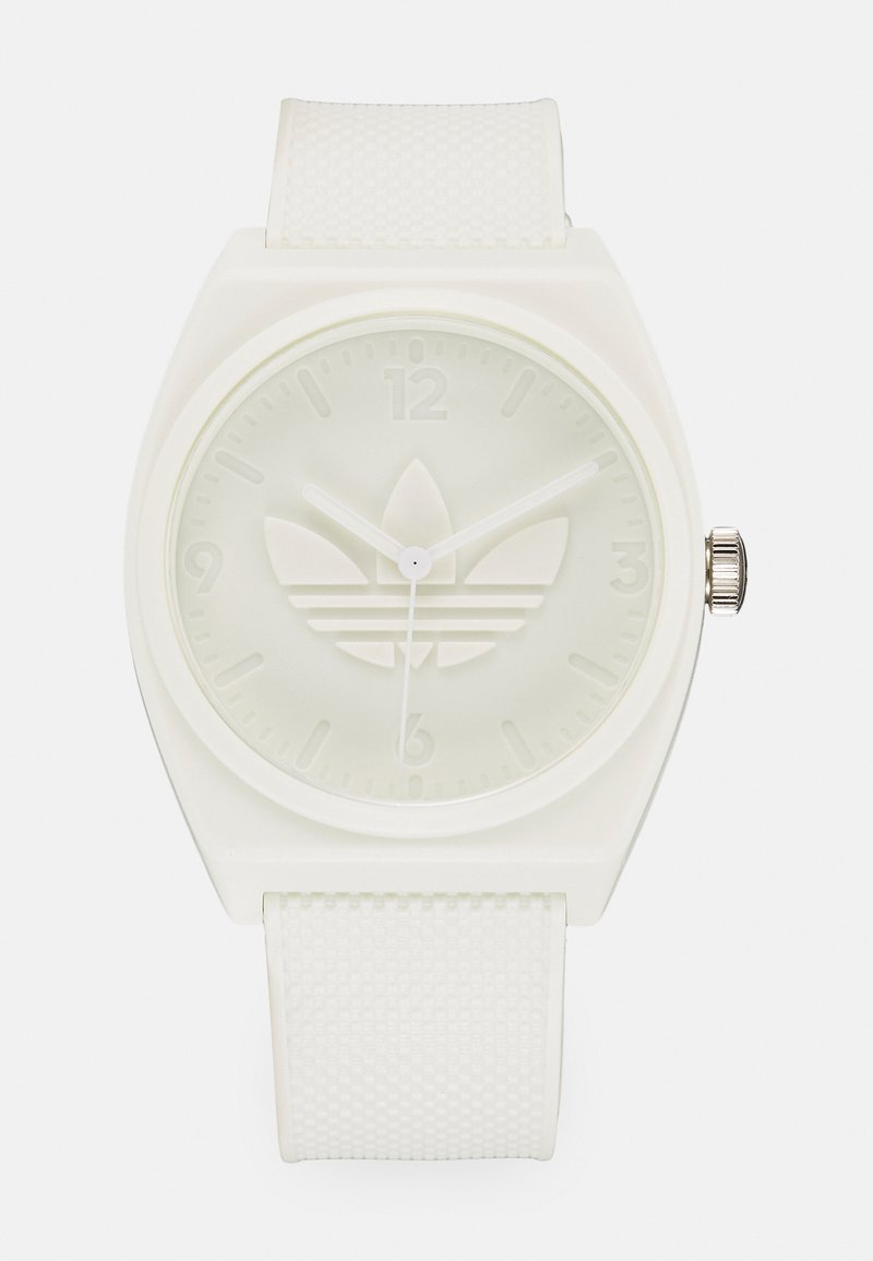 Montre en silicone blanche avec un cadran carré, un bracelet texturé et un logo en relief. Le cadran minimaliste présente des index horaires et des aiguilles simples.