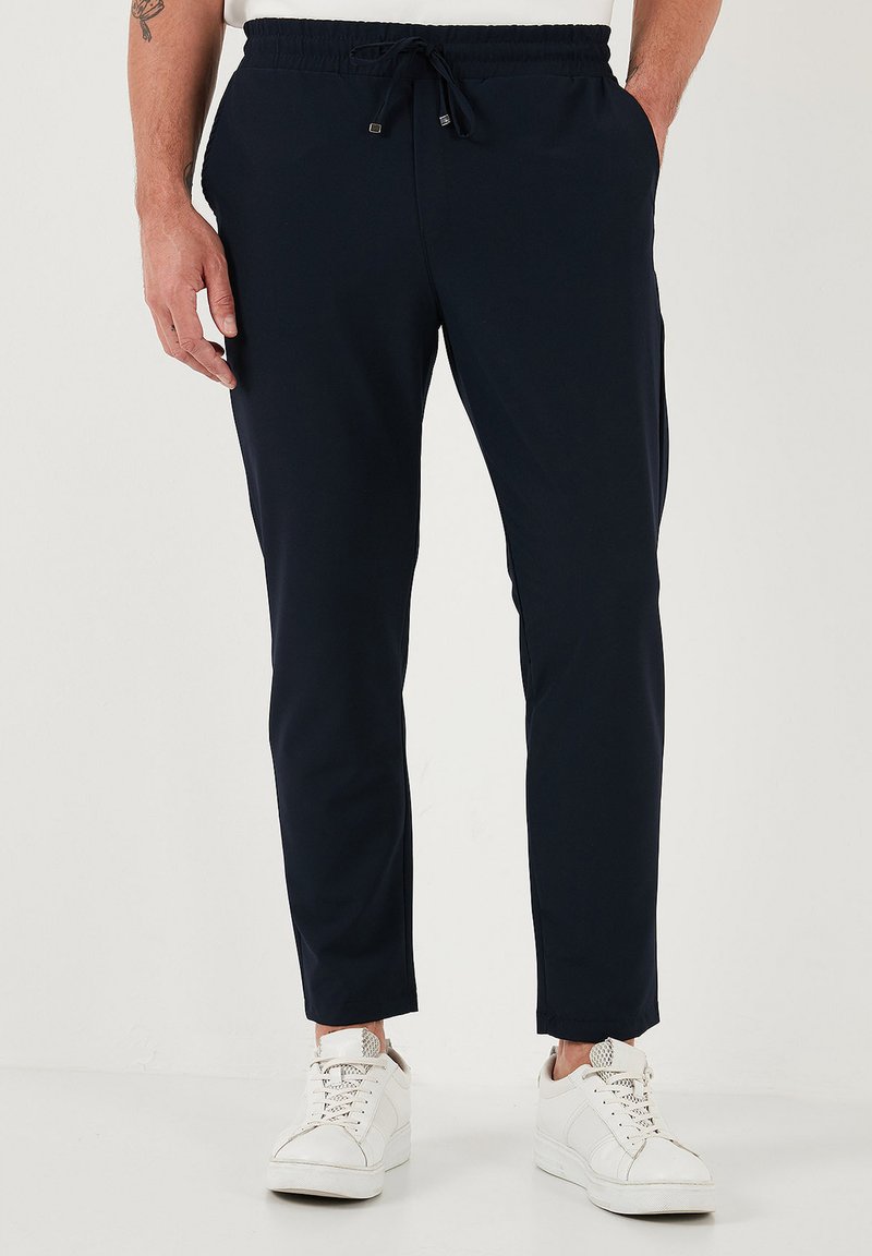 Marine joggerbroek met een elastische tailleband, trekkoordsluiting en taps toelopende benen. Draag ze met witte sneakers, uitgevoerd met zijzakken.