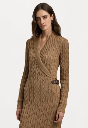 Abito avvolgente in maglia a treccia color beige, con scollatura a V profonda, maniche lunghe e dettaglio in pelle con fibbia in vita. Motivo a maglia testurizzato su tutta la superficie.