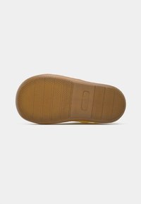 Εξωτερική σόλα παπουτσιού από καουτσούκ σε καφέ χρώμα με υφή και μοτίβο λαβής. Διαθέτει οριζόντιες ραβδώσεις και ένα μικρό χαραγμένο λογότυπο κοντά στη φτέρνα.