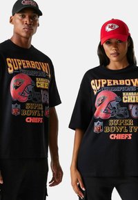 T-shirts surdimensionnés noirs avec des graphismes des Super Bowl des Kansas City Chiefs dans des couleurs vives. Accompagnés d'une casquette rouge arborant le logo de l'équipe.