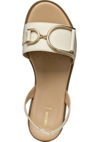 Sandalia de deslizar blanca con una tira ancha, que presenta un acento en tono dorado. Parte superior de cuero suave, plantilla acolchada y diseño de punta abierta.