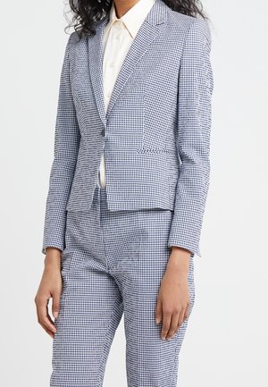 Blazer a scacchi in tessuto intrecciato, con un design aderente, rever a punte, chiusura con un solo bottone e tasche frontali.
