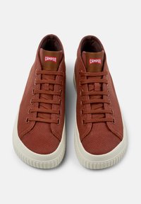 Brown fabric sneakers with a textured finish, featuring a white rubber sole, round toe, and classic lacing. Red "CAMPER" branding on the tongue.