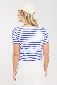 Biała bluzka z krótkim rękawem w niebieskie poziome paski, z szerokim dekoltem. Tył jest lekko skrócony i ma gładką fakturę.