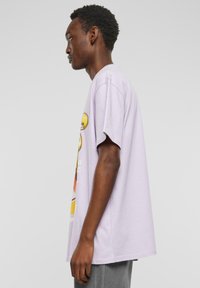 Lyselilla oversized t-shirt lavet af bomuld, med grafisk print og korteærmer. Struktureret stof med en afslappet pasform og faldende skuldre.
