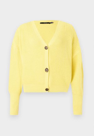 Κίτρινη κοντή ζακέτα με V-λαιμόκοψη, ραβδωτή υφή και τρία ξύλινα κουμπιά μπροστά. Μακριά μανίκια, ελαφρύ πλεκτό υλικό.