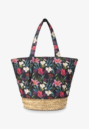 Bloemen tote bag in donkere stof met roze en witte bloemen, geweven rieten basis, dubbele handgrepen en decoratief rond embleem.