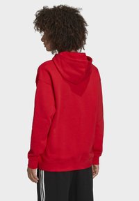 Röd huvtröja med avslappnad passform, ribbade ärmslut och nederkant, med enfärgad design, mjuk textur och en medelhög huva.