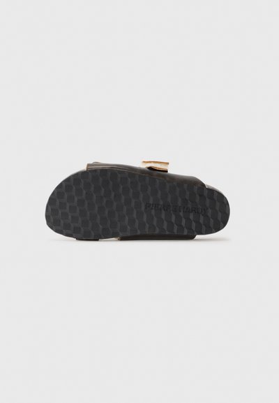 Black rubber shoe sole with a honeycomb texture, featuring a gold metallic accent at the side, branded "PIERRE HARDY" on the underside.
