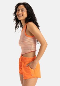 Orange crop top with horizontal blue stripes and a scalloped hem, paired with orange drawstring shorts featuring a pocket and frayed edges.