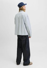 Hellblaue und weiße karierte Overshirt mit entspannter Passform, kombiniert mit dunkelblauen weiten Jeans und einer navyblauen Mütze. Natürliche Textur und lässiges Design.
