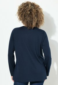 Top a maniche lunghe navy realizzato in tessuto morbido, con scollo rotondo e vestibilità comoda. Texture liscia senza motivi o accenti visibili.