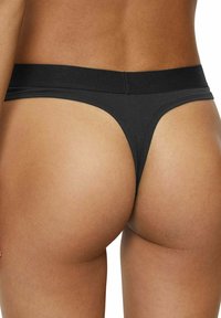 Perizoma nero in tessuto liscio, con una ampia cintura elastica e un design minimalista sul retro.