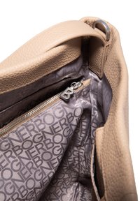 Intérieur de sac à main en cuir beige avec une poche zippée. Texture douce et doublure à motifs logo en gris clair. Accessoires métalliques lisses.