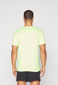 Camiseta atlética de manga corta verde neón con cuello redondo. Textura suave con un ligero brillo, diseñada para el uso activo.