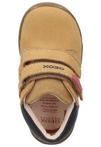 Zapato de cuero marrón para niño pequeño con dos correas de Velcro, forro suave, puntera redondeada y suela de goma; presenta el logo de la marca cerca de las correas.