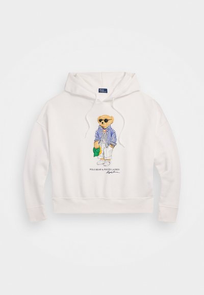 Hvid hoodie med ribbet kant, prydet med en broderet bjørn iført et stribet jakkesæt, solbriller og afslappet påklædning, med logoet under.