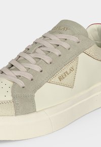 Baskets basses crème et beige avec détails en daim, lacets plats et logo "REPLAY" sur le côté et la languette.
