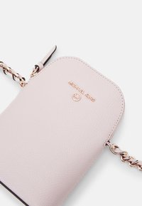 Borsa a tracolla in pelle rosa chiaro con una parte superiore arrotondata, caratterizzata da un logo in tonalità oro e una tracolla a catena. Superficie testurizzata con dettagli di cucitura visibili.
