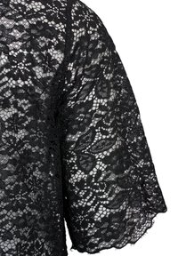 Top in pizzo nero con motivi floreali, texture trasparente e maniche corte. Dettagli intricati con design a trama aperta e finitura morbida.
