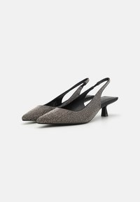 Escarpins à talon moyen avec un bout pointu, recouverts de rhinestones métalliques, avec un intérieur noir et un talon bloc modeste.